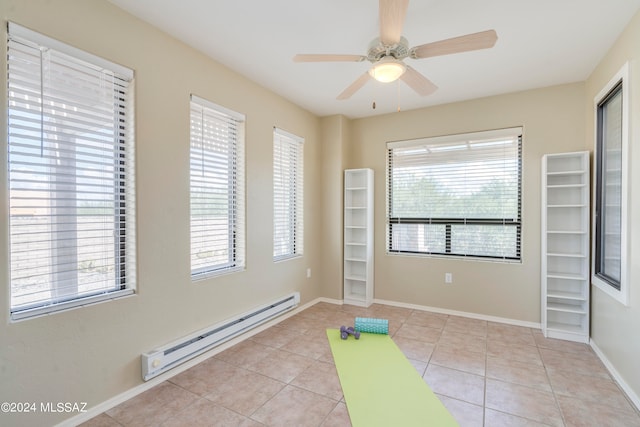 exercise area featuring a wealth of natural light, ceiling fan, baseboard heating, and light tile patterned flooring