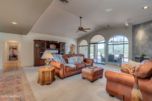 tiled living room with ceiling fan, lofted ceiling, and tile walls