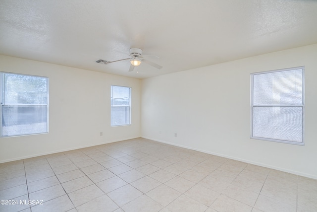 spare room featuring ceiling fan, light tile patterned flooring, and a healthy amount of sunlight