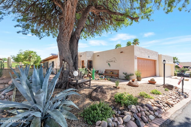 pueblo-style home with a garage and stucco siding