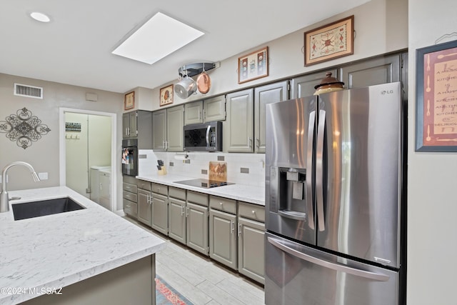 kitchen featuring visible vents, gray cabinets, a sink, and black appliances