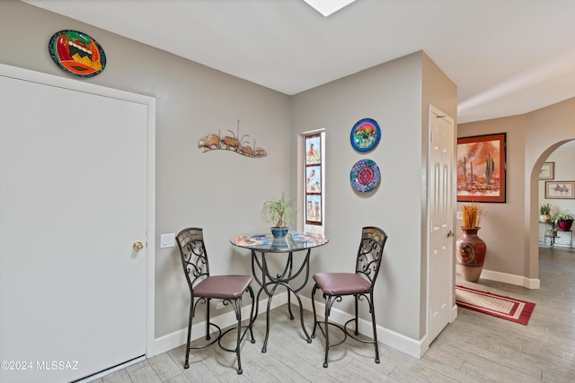 dining room with arched walkways, wood finished floors, and baseboards