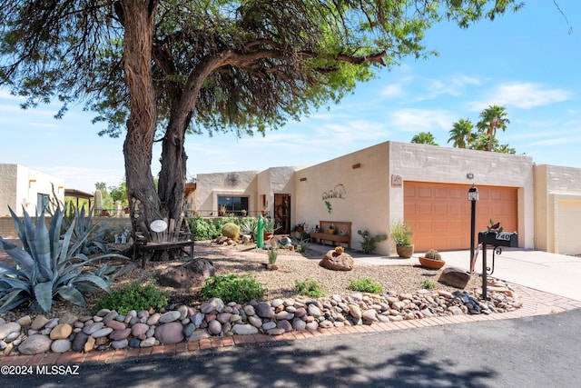 pueblo-style home featuring a garage, stucco siding, and concrete driveway