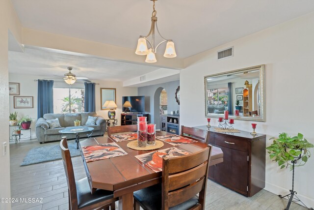 dining space with visible vents, arched walkways, light wood-style floors, and ceiling fan