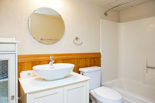 full bathroom with toilet, wooden walls, shower / washtub combination, and vanity