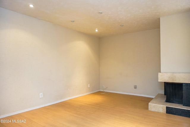 unfurnished living room with a premium fireplace, wood-type flooring, and a textured ceiling