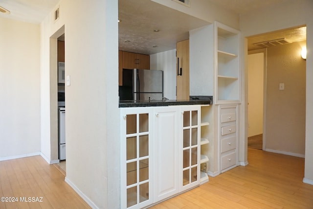 kitchen with stainless steel fridge and light hardwood / wood-style floors