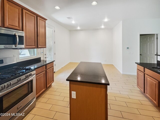 kitchen with visible vents, a kitchen island, recessed lighting, appliances with stainless steel finishes, and brown cabinetry