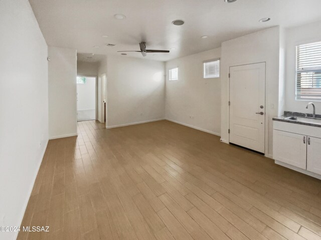 spare room with a sink, baseboards, a ceiling fan, and light wood finished floors