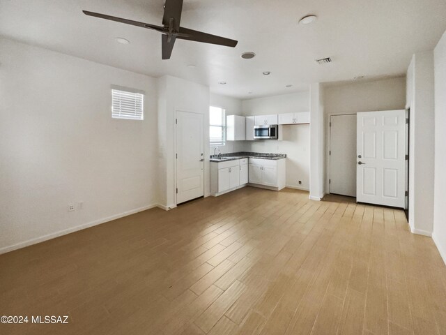 kitchen featuring a ceiling fan, visible vents, light wood finished floors, white cabinets, and stainless steel microwave