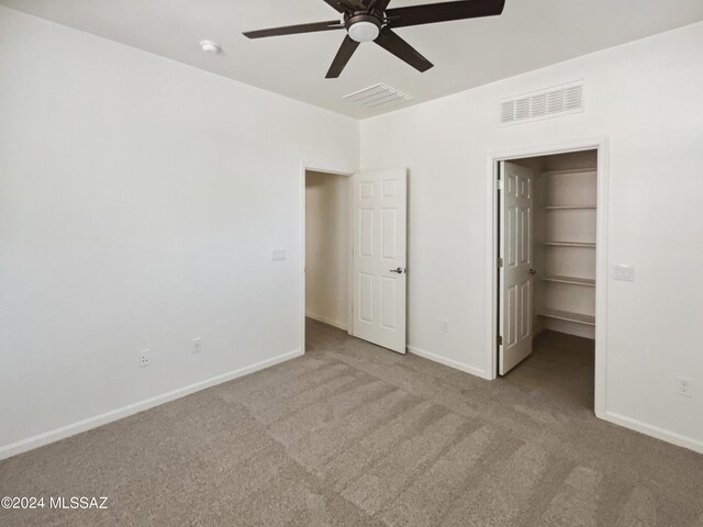 unfurnished bedroom with a walk in closet, carpet, visible vents, and baseboards