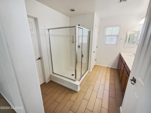 full bathroom featuring wood finish floors, visible vents, a stall shower, baseboards, and vanity