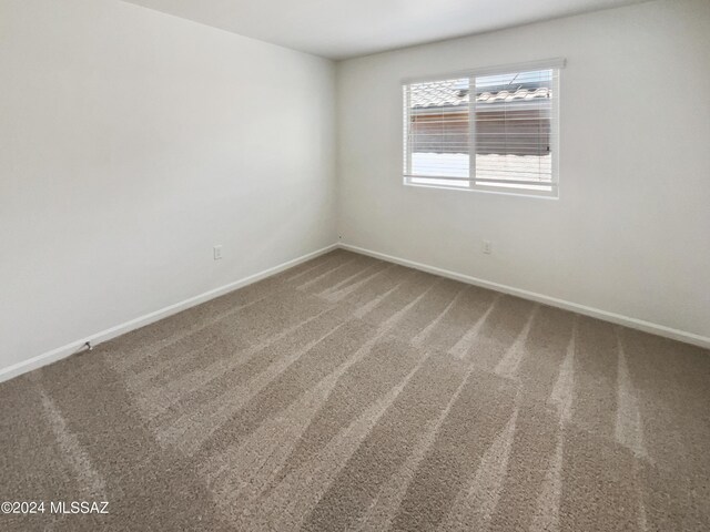 unfurnished room featuring carpet flooring and baseboards