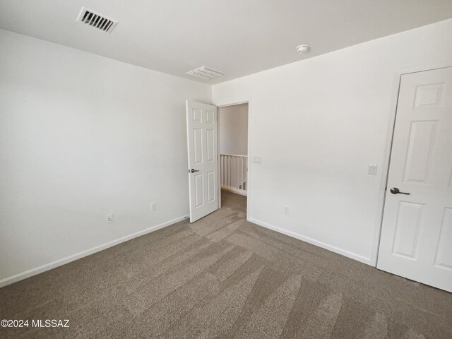 carpeted empty room featuring visible vents and baseboards