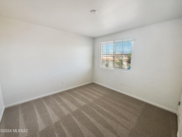 carpeted spare room featuring baseboards