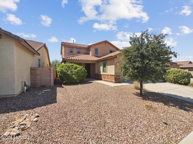 mediterranean / spanish home with fence, stucco siding, concrete driveway, stone siding, and a tile roof