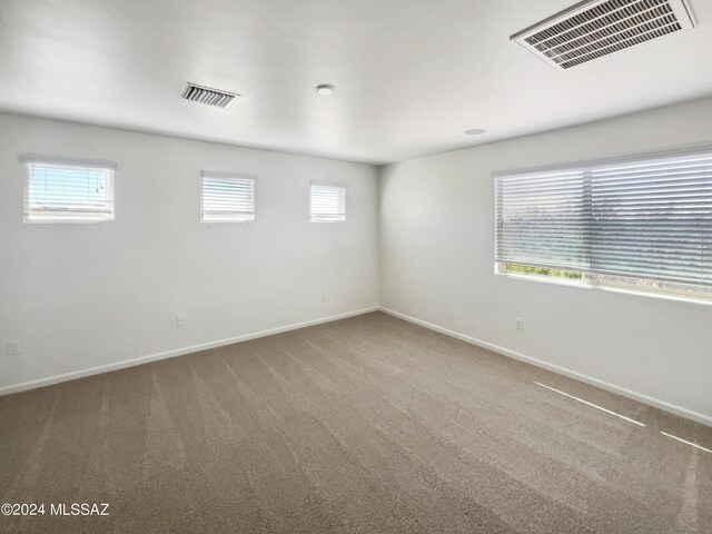 unfurnished room featuring visible vents, baseboards, and carpet