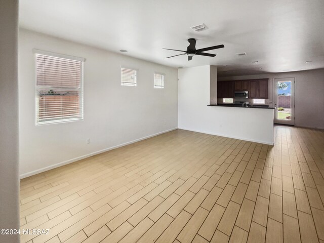 unfurnished living room with a ceiling fan, light wood-style floors, visible vents, and baseboards