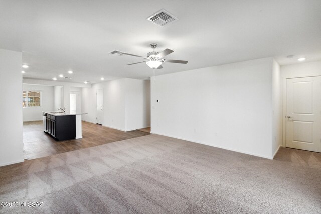 unfurnished living room with carpet, ceiling fan, and sink