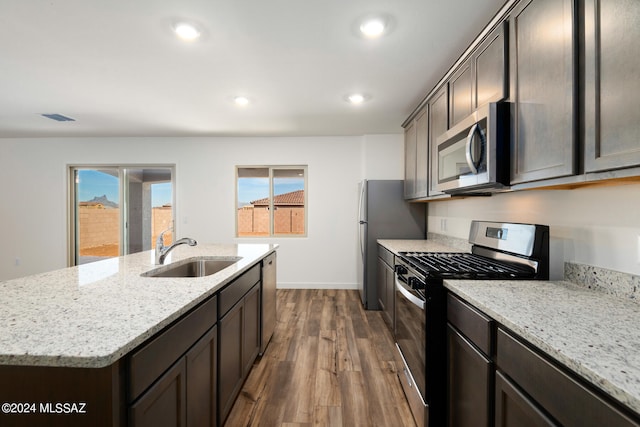 kitchen featuring light stone counters, stainless steel appliances, sink, dark hardwood / wood-style floors, and a kitchen island with sink