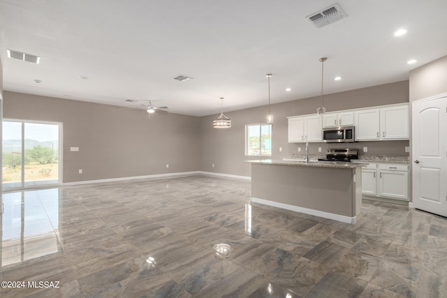 kitchen with a center island with sink, pendant lighting, stainless steel appliances, white cabinetry, and ceiling fan