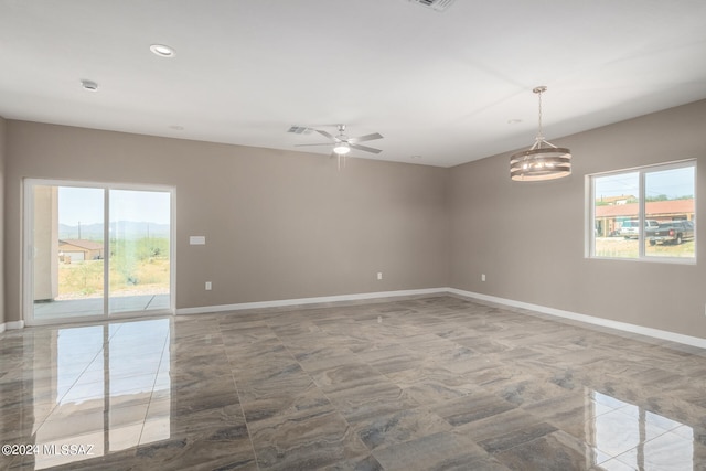 empty room featuring ceiling fan with notable chandelier