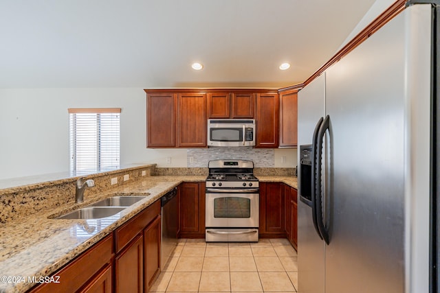 kitchen with light tile patterned floors, appliances with stainless steel finishes, light stone countertops, sink, and kitchen peninsula