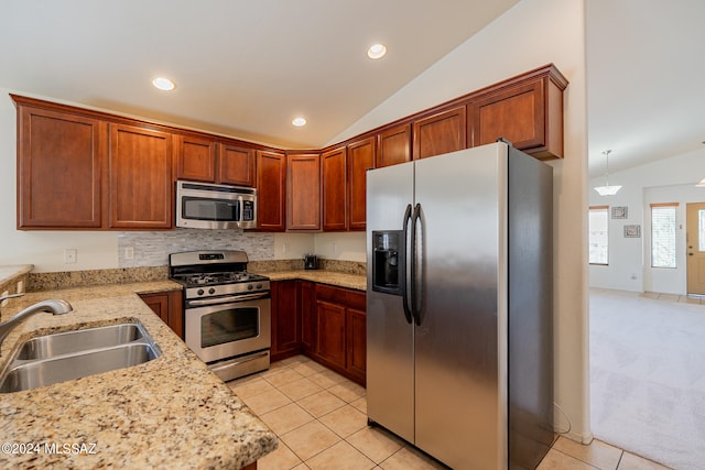 kitchen with vaulted ceiling, light stone counters, stainless steel appliances, and sink