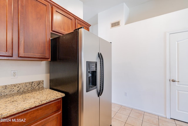 kitchen featuring stainless steel fridge with ice dispenser, light stone counters, and light tile patterned floors