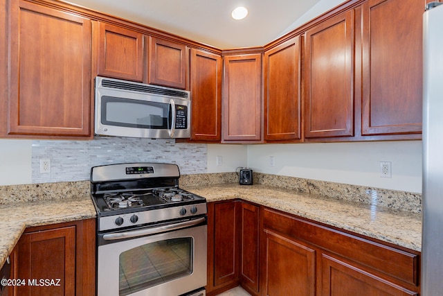 kitchen with light stone counters and appliances with stainless steel finishes