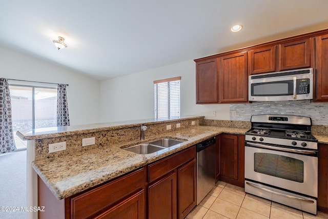 kitchen with stainless steel appliances, kitchen peninsula, sink, light stone countertops, and lofted ceiling