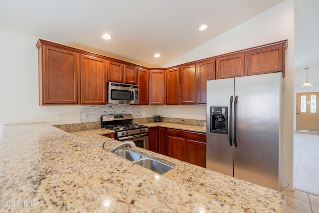 kitchen featuring light stone countertops, stainless steel appliances, sink, and vaulted ceiling