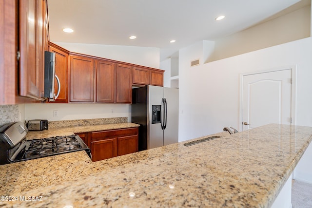 kitchen with vaulted ceiling, light stone counters, stainless steel appliances, sink, and kitchen peninsula