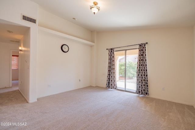 spare room featuring lofted ceiling and light colored carpet