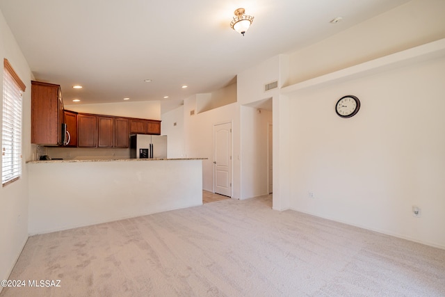 kitchen featuring light colored carpet, stainless steel appliances, kitchen peninsula, and vaulted ceiling