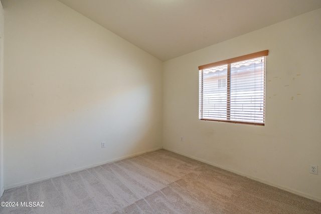 carpeted spare room with vaulted ceiling