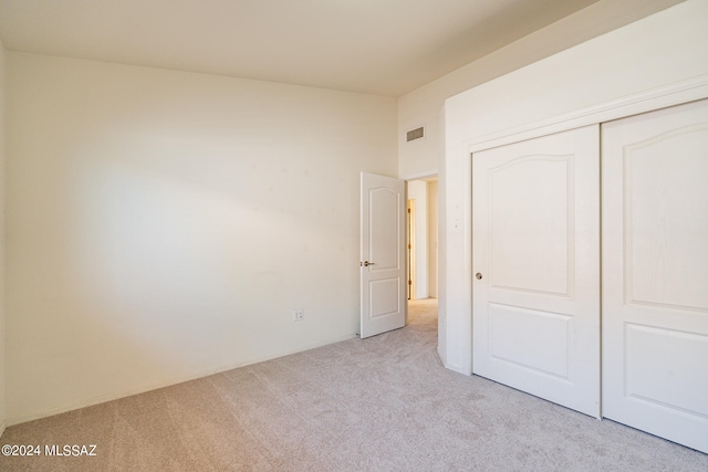 unfurnished bedroom with a closet and light carpet