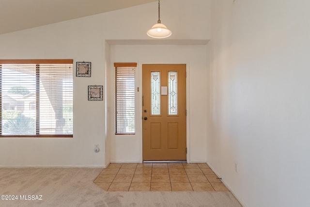 foyer entrance with vaulted ceiling and light carpet