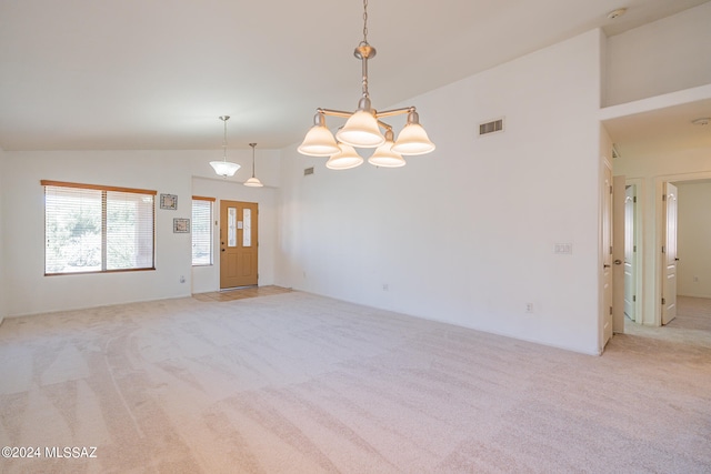 empty room with high vaulted ceiling, a notable chandelier, and light carpet