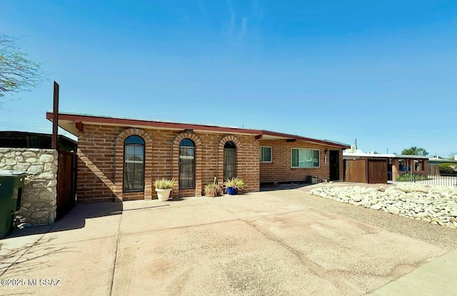 ranch-style house featuring brick siding and fence