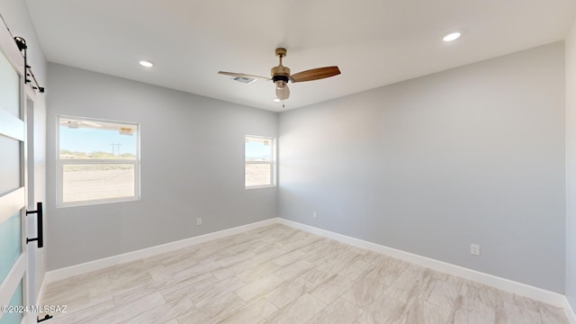 spare room featuring a barn door and ceiling fan