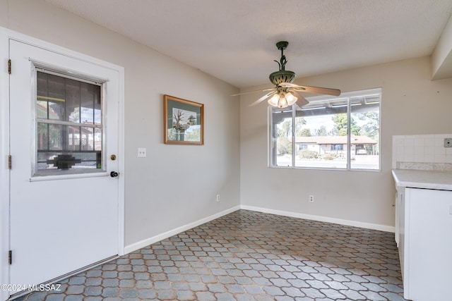 unfurnished dining area featuring ceiling fan and a textured ceiling