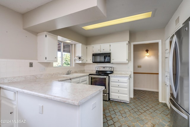 kitchen with white cabinetry, sink, kitchen peninsula, decorative backsplash, and appliances with stainless steel finishes