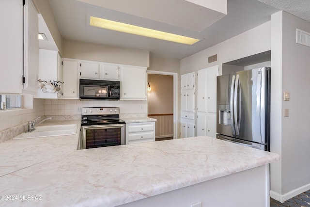 kitchen with kitchen peninsula, sink, white cabinets, and stainless steel appliances