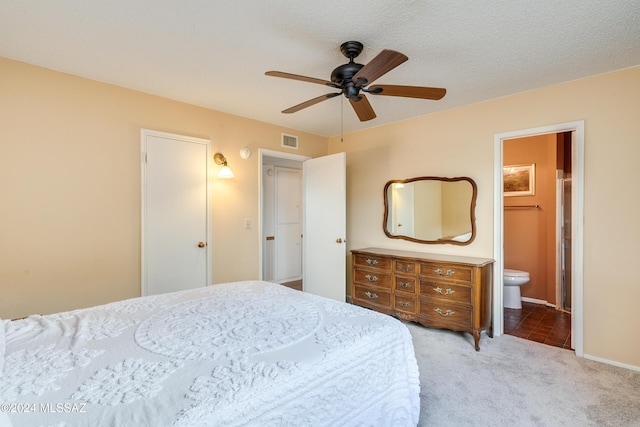 bedroom featuring a textured ceiling, ceiling fan, light carpet, and ensuite bath