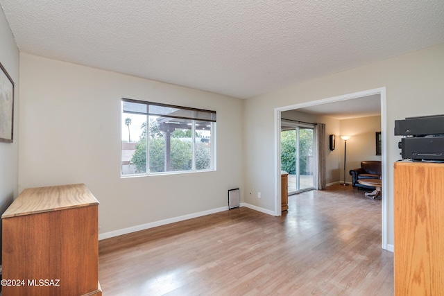 unfurnished room with a textured ceiling and light wood-type flooring