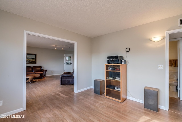 hall featuring light wood-type flooring and a textured ceiling