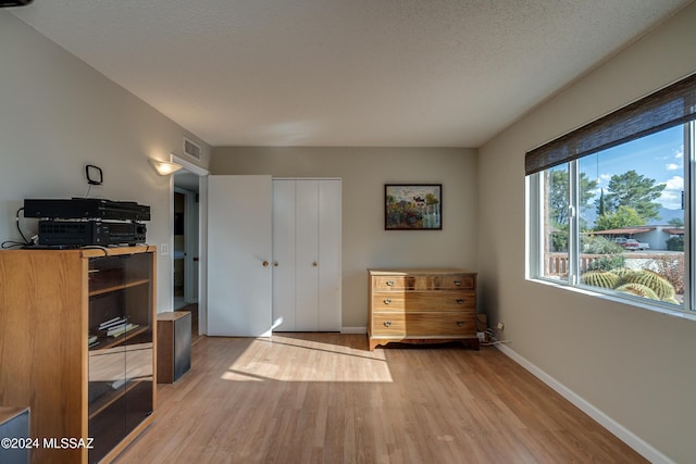 bedroom with a closet, a textured ceiling, and hardwood / wood-style flooring