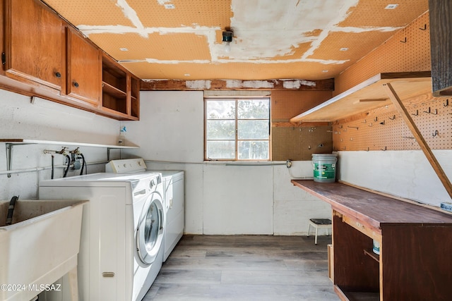 laundry area featuring cabinets, separate washer and dryer, sink, and light hardwood / wood-style flooring