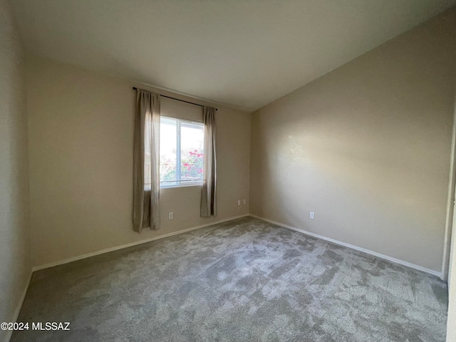 carpeted spare room with lofted ceiling